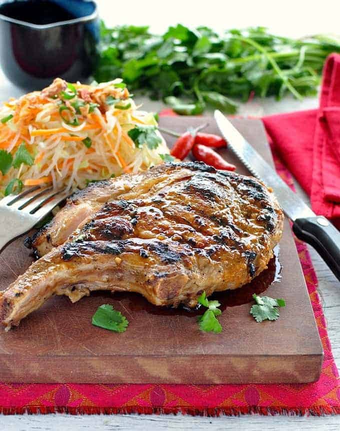Vietnamese pork chop on a wooden board with papaya salad