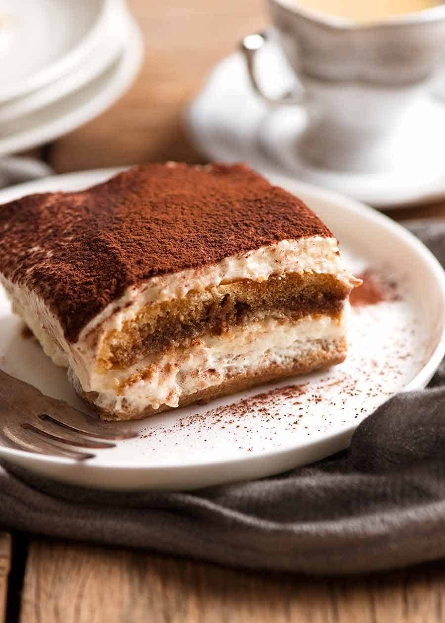 Close up of a slice of Tiramisu on a white plate, ready to be eaten