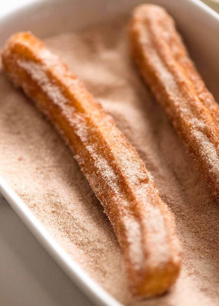 Close up of chutoss being coated with cinnamon and sugar