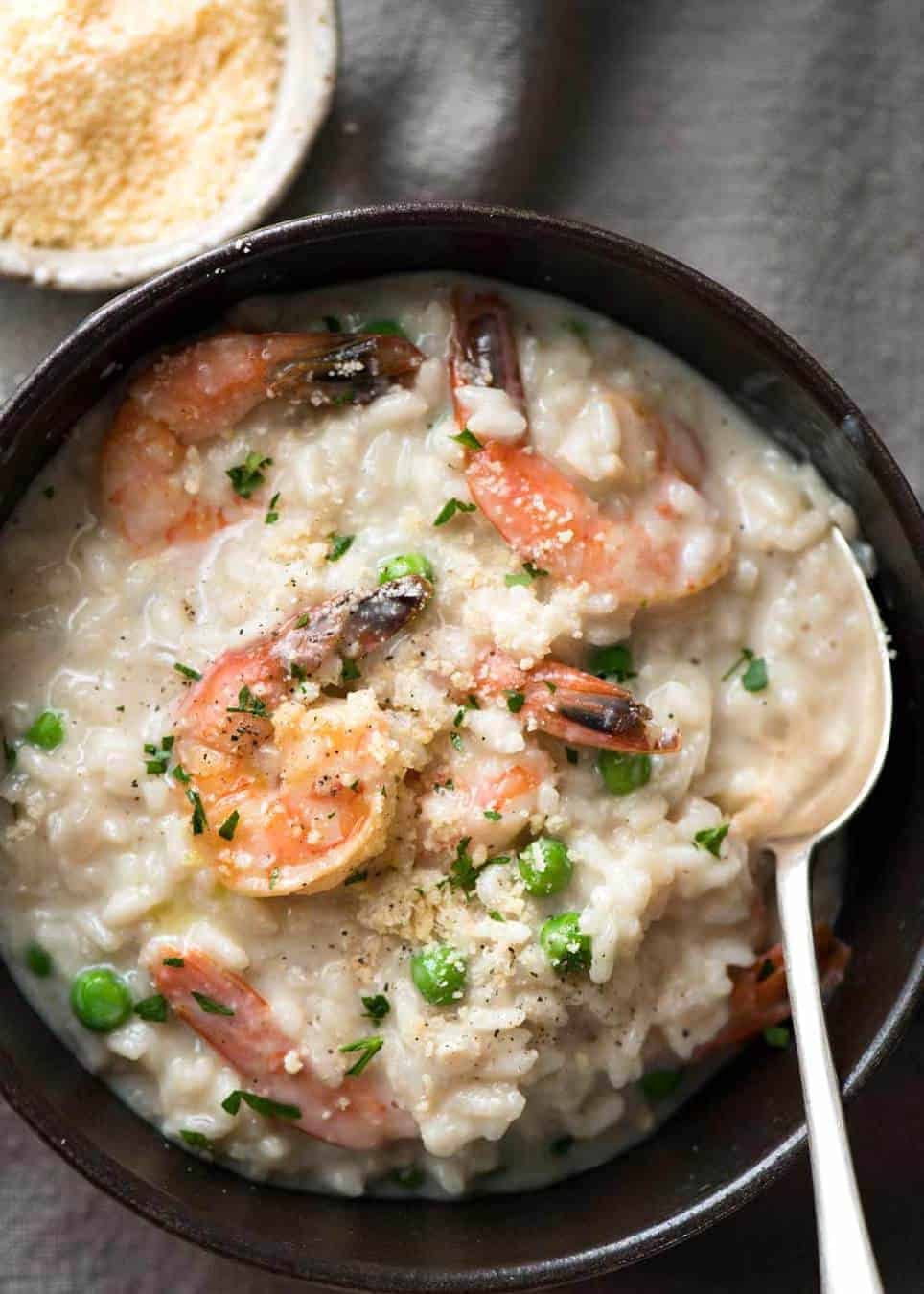 Overhead photo of Prawn Risotto (Shrimp Risotto) in a dark brown bowl, ready to be eaten.