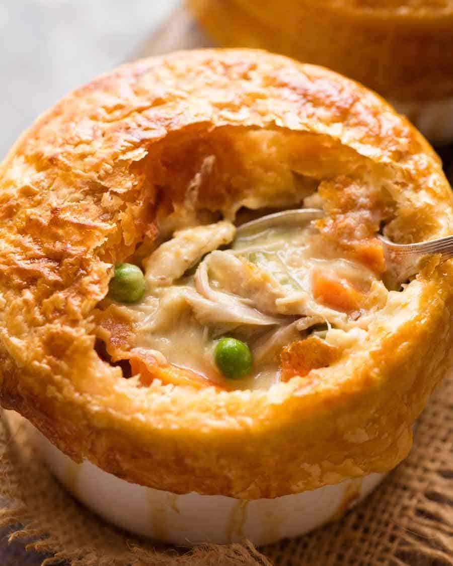 Close up of Chicken Pot Pie in a ramekin with puff pastry topping, made from scratch with uncooked chicken.