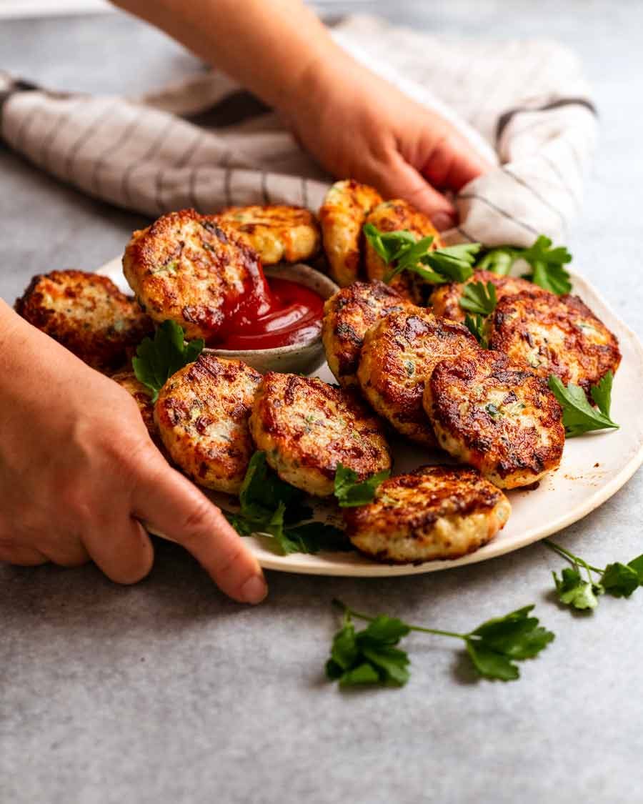 Putting a platter of Chicken rissoles (chicken patties) on the table