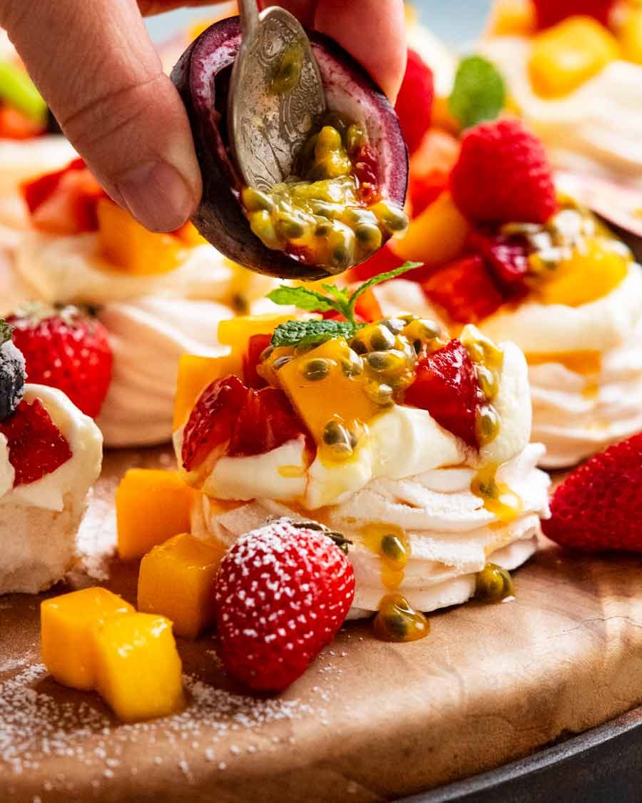Putting passionfruit topping on Mini Pavlovas